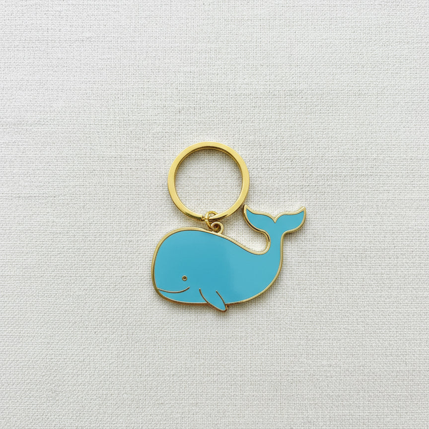 Blue whale-shaped keychain on a light gray background