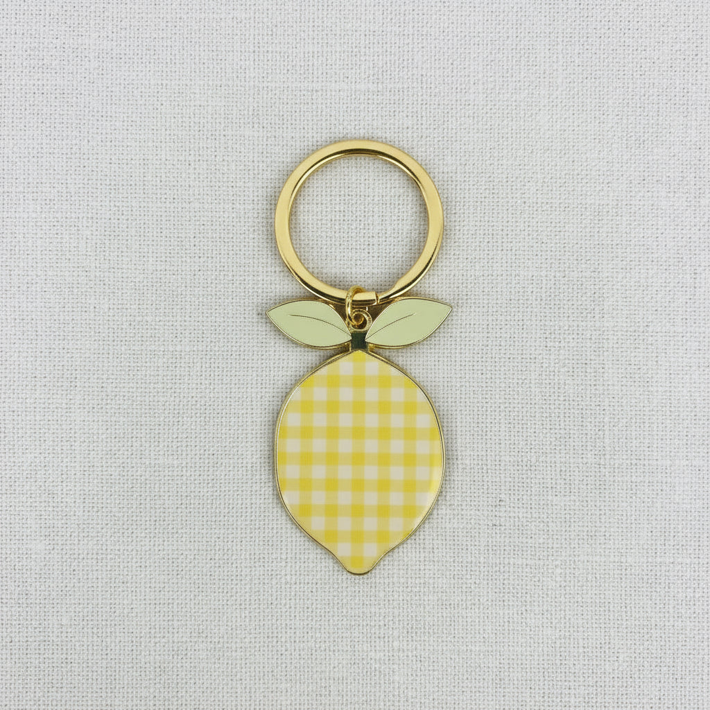 Yellow checkered lemon-shaped keychain on a light gray background